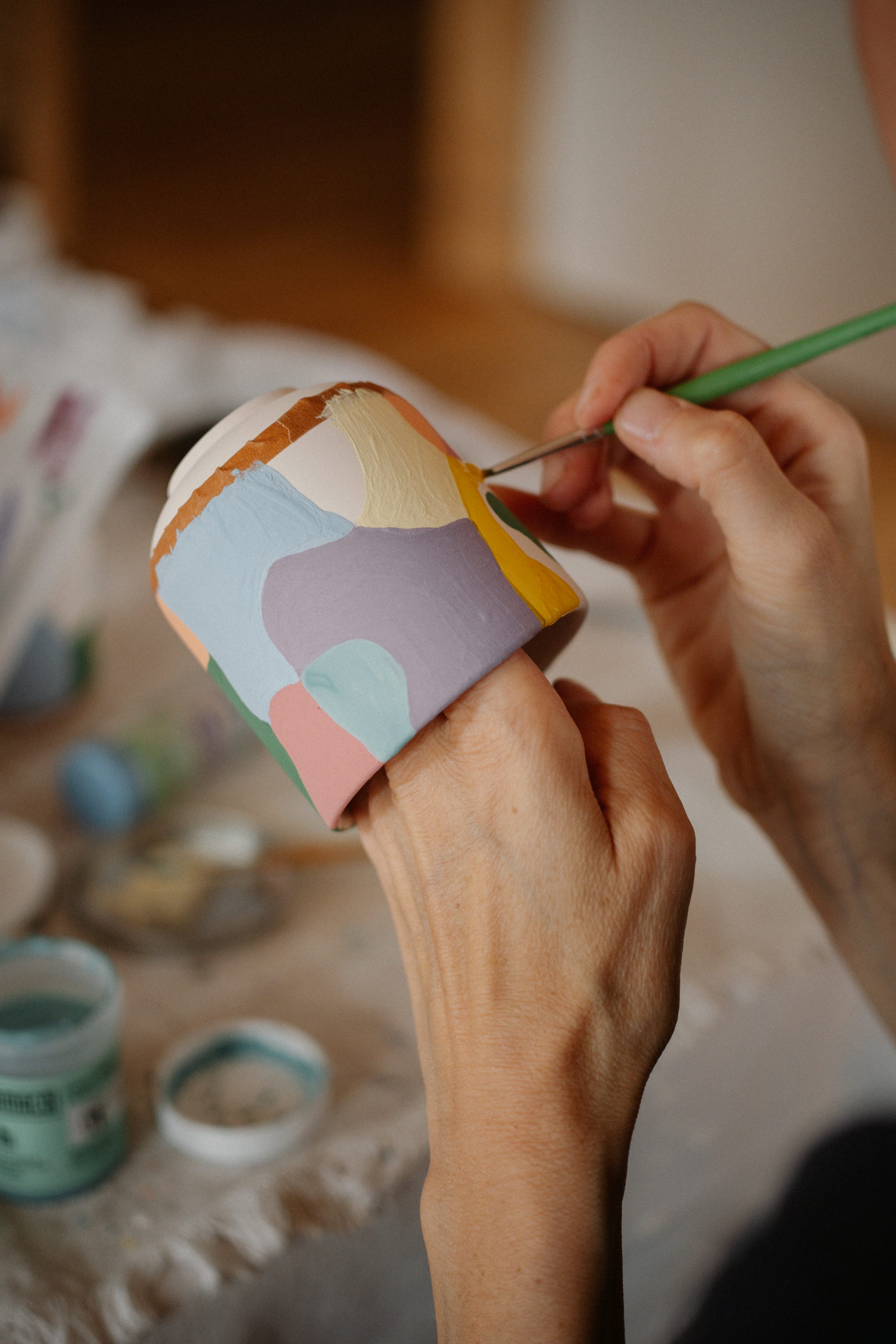 Hands painting a colorful custom cup — the heart of DAEZ INK